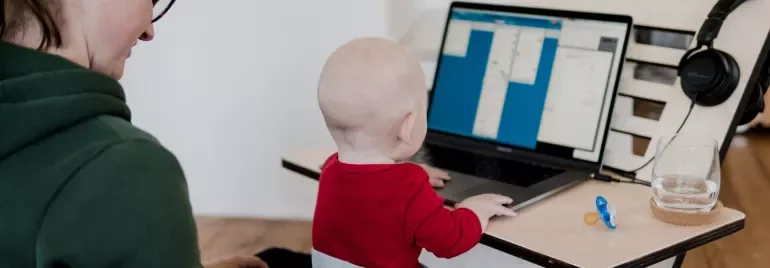 Adult with child on lap, looking at a laptop.