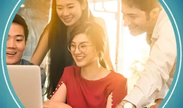 Group of people smiling and looking at a laptop together.